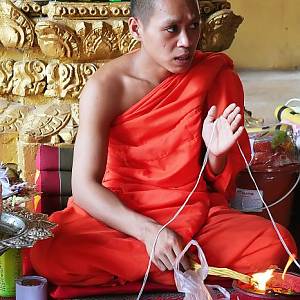 Mnich provádějící obřad Khwan baci v chrámu Wat Si Muang
