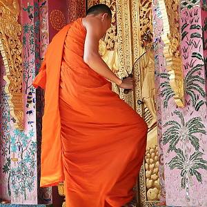 Mnich zavírá Wat Xieng Thong